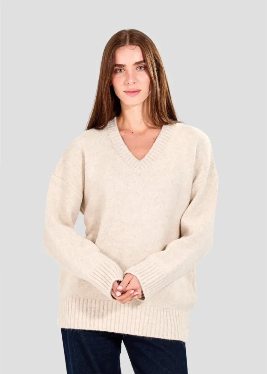 Woman wearing a cream sweater against a light gray background