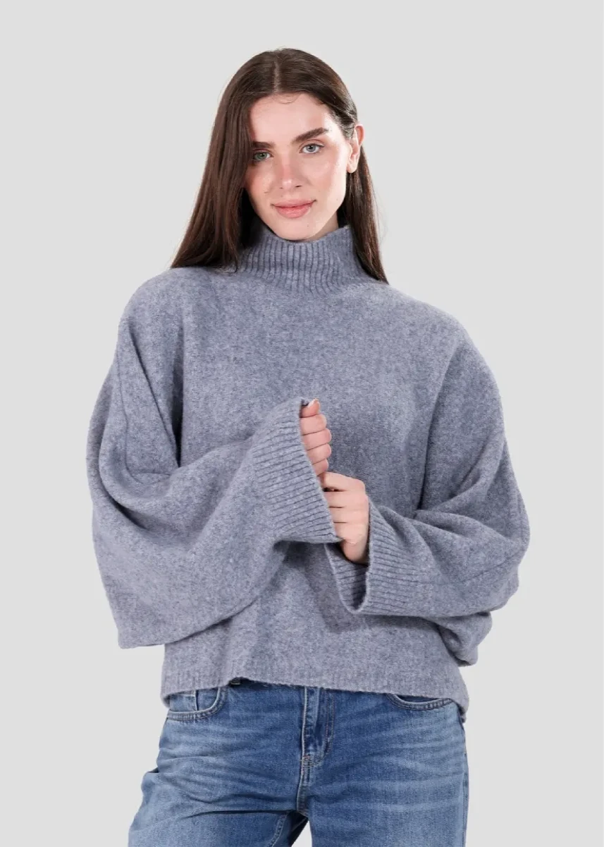 Woman wearing a gray sweater and blue jeans on a light gray background
