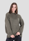 Woman wearing a green sweater against a plain background