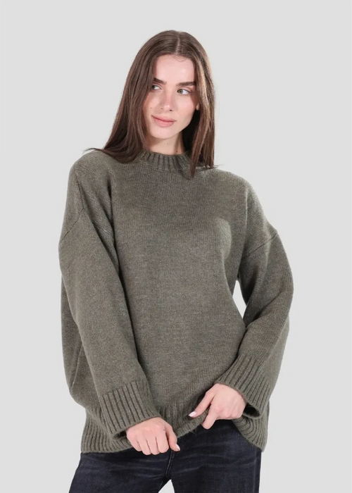 Woman wearing a green sweater against a plain background