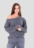 Woman wearing a gray off-shoulder sweater and jeans on a light gray background