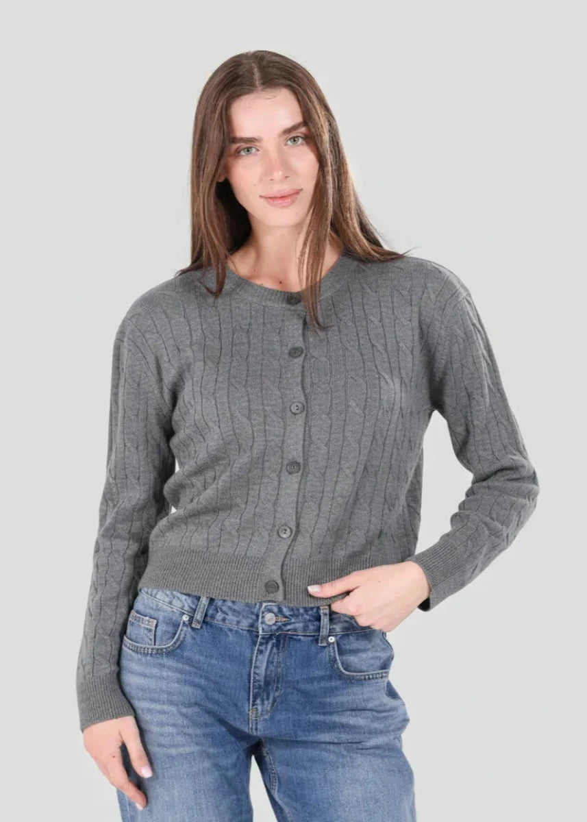 Woman wearing a gray ribbed sweater and blue jeans on a plain background