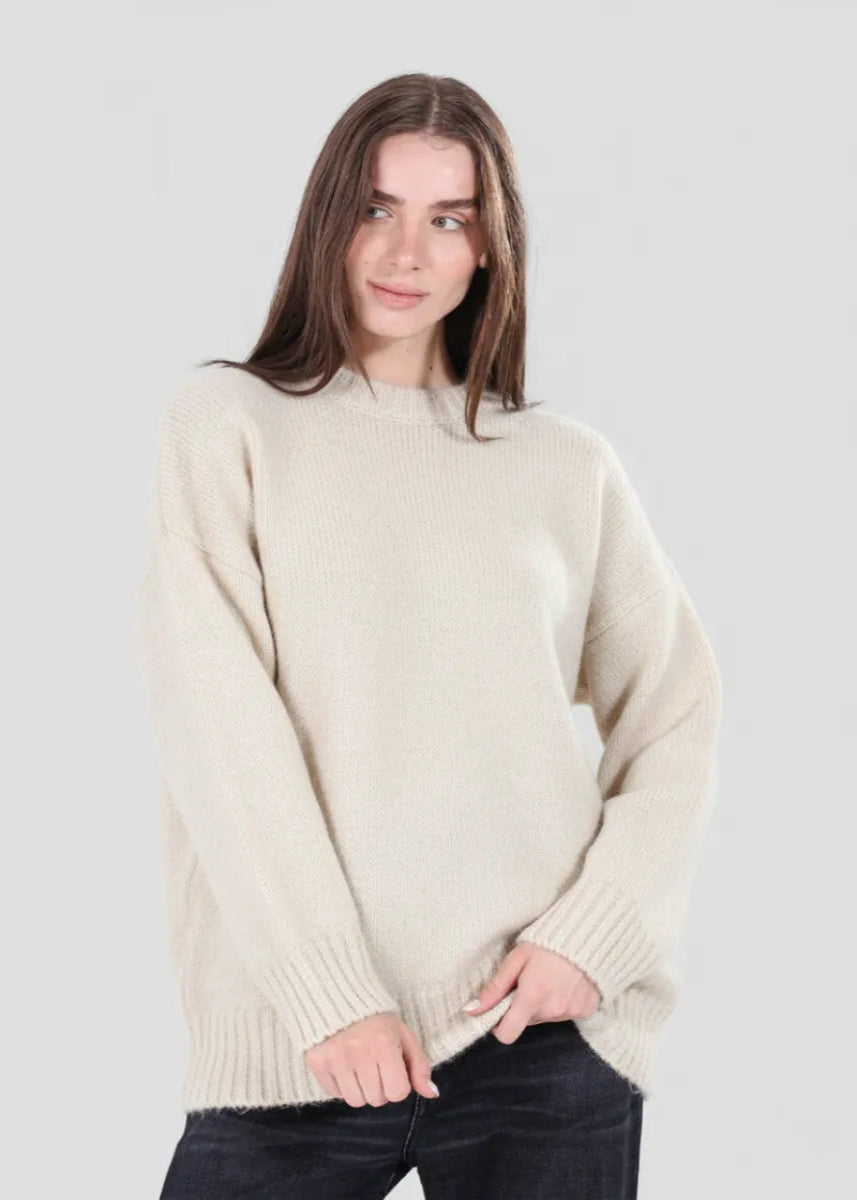 Woman wearing a beige sweater against a plain background