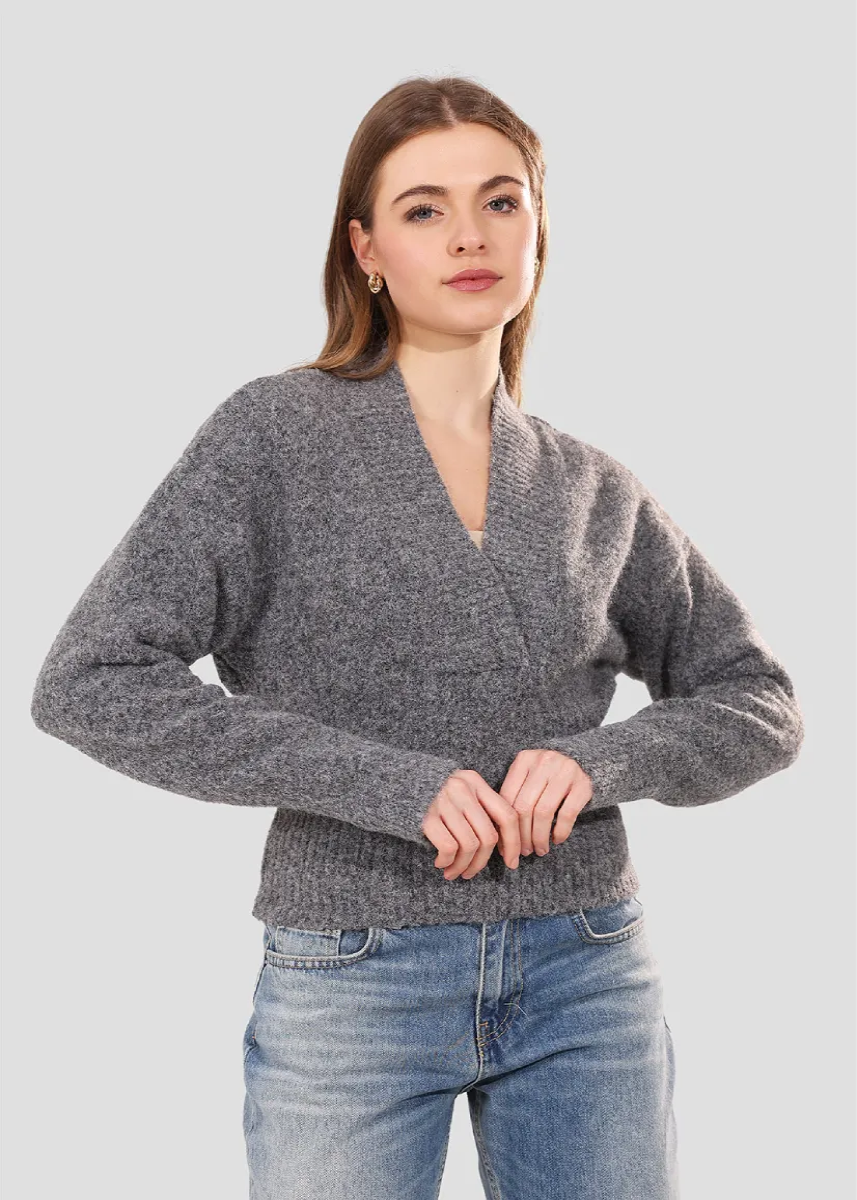 Woman wearing a gray sweater and blue jeans on a light gray background