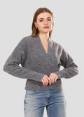 Woman wearing a gray sweater and blue jeans on a light gray background