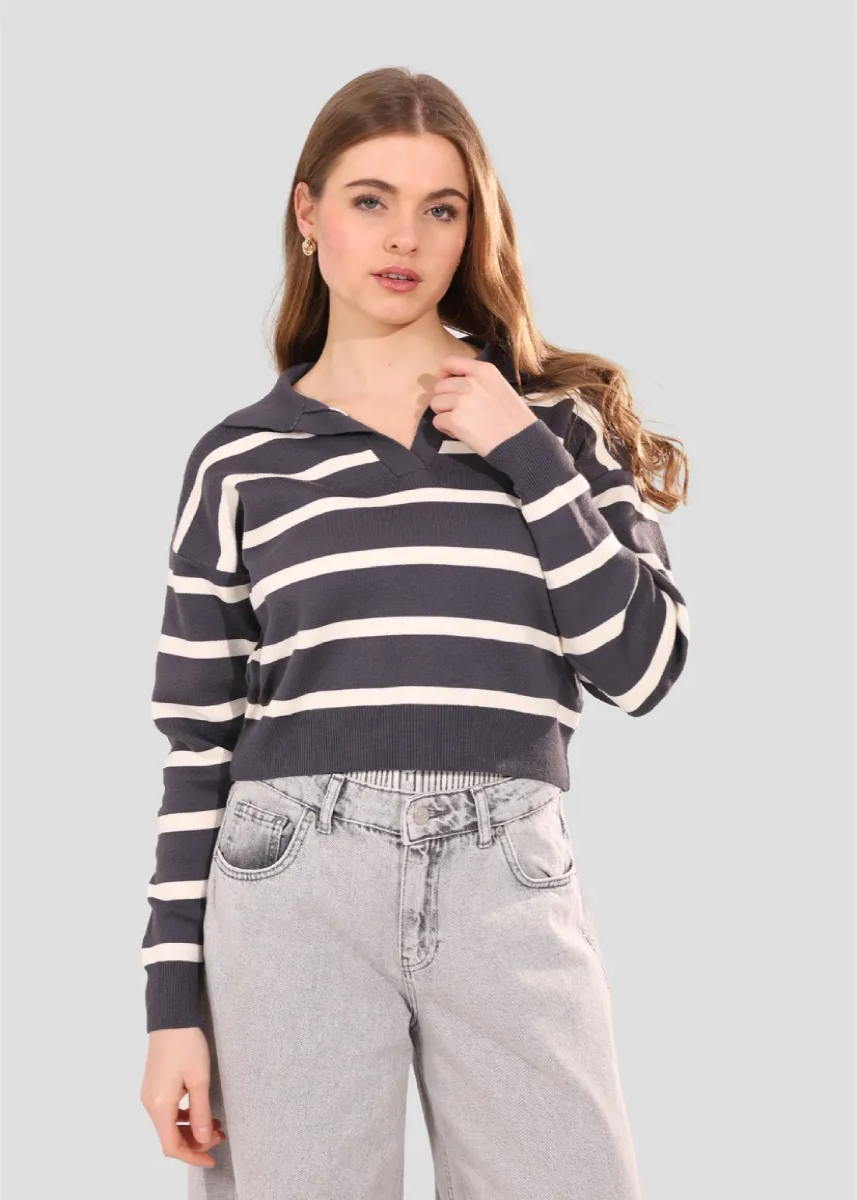 Woman wearing a striped sweater and jeans on a plain background