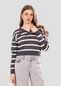 Woman wearing a striped sweater and jeans on a plain background